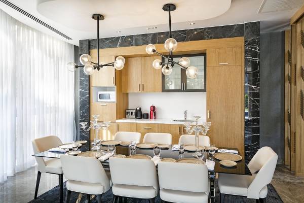 Speisezimmer im Titanic Luxury Collection Bodrum mit Esstisch, weißen Stühlen und Kronleuchtern.