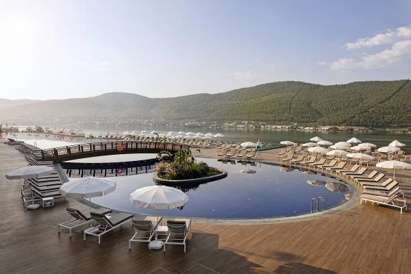 Poolbereich des Titanic Luxury Collection Bodrum Hotels mit Sonnenliegen und Schirmen.