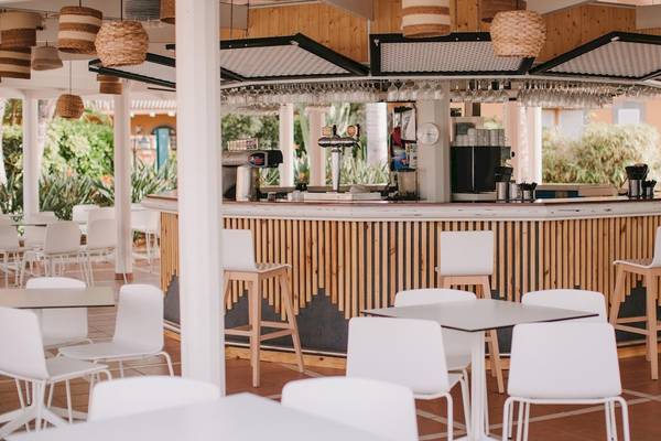 Barbereich im Suites & Villas By Dunas Hotel mit weißen Stühlen und Tischen.