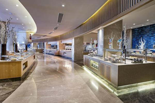 Innenansicht des Restaurants im Titanic Luxury Collection Bodrum mit mehreren Essenstheken und dekorativen Elementen.