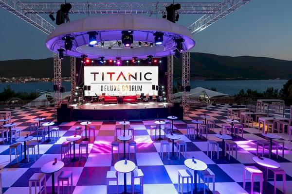 Abendveranstaltung auf der Bühne des Titanic Luxury Collection Bodrum mit roten Sofas und blau-weiß-gemustertem Boden.