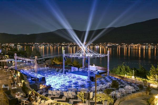 Abendveranstaltung am Wasser im Titanic Luxury Collection Bodrum mit beleuchteter Bühne und Sitzbereichen.