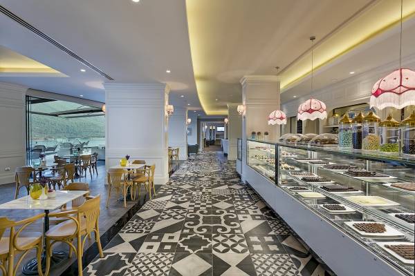 Innenansicht des Titanic Luxury Collection Bodrum Hotels mit gemusterten Bodenfliesen und Tisch-Sitz-Arrangement.