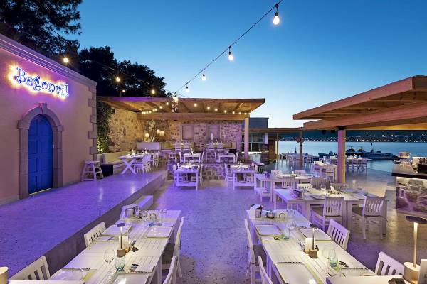 Abendliche Terrasse des Hotels Begonvil mit beleuchteten Tischen und Stühlen, Blick auf das Meer.
