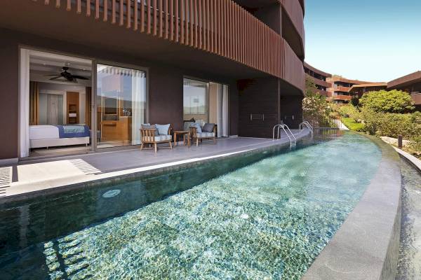 Außenbereich des Titanic Luxury Collection Bodrum mit Swimmingpool und Sitzbereich.