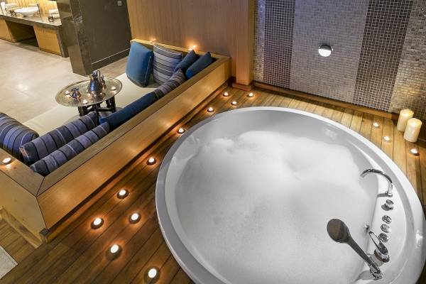 Badezimmer im Titanic Luxury Collection Bodrum mit Whirlpool, Sitzbank und blauen Kissen.