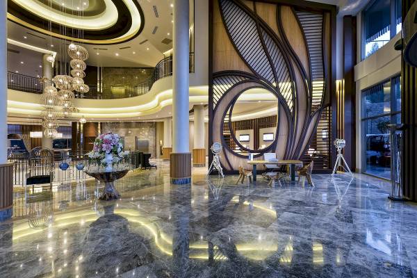 Foyer des Titanic Luxury Collection Bodrum Hotels mit Blumen, Tisch und Skulptur.