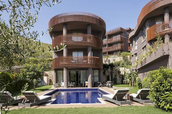 Außenbereich des Titanic Luxury Collection Bodrum mit Pool, Liegestühlen und Bäumen.