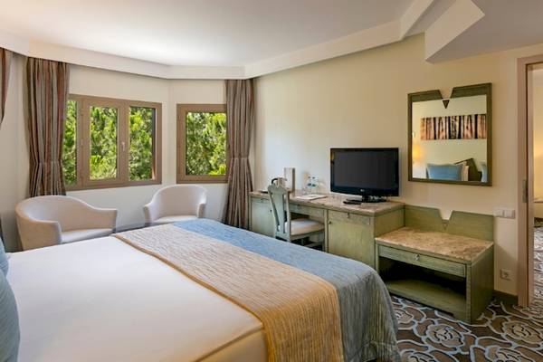 Zimmer im Xanadu Resort Hotel mit Bett, Schreibtisch, Fernseher und zwei Fenstern.