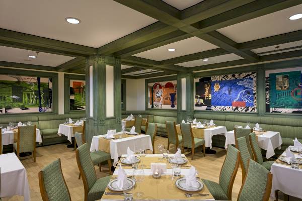 Restaurantbereich des Xanadu Resort Hotels mit grünen Wänden, großen Gemälden und gedeckten Tischen.