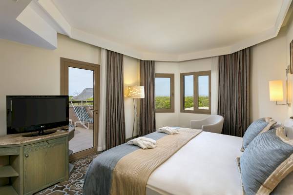 Xanadu Resort Hotel Zimmer mit Fernseher, Bett, Sessel und Fenstern.