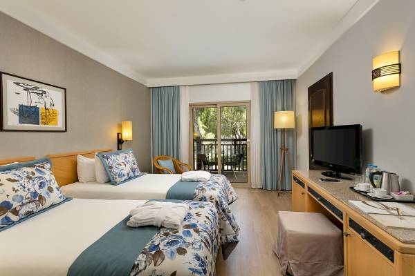Doppelzimmer im Xanadu Resort Hotel mit zwei Betten, Balkon und Blick auf Bäume.