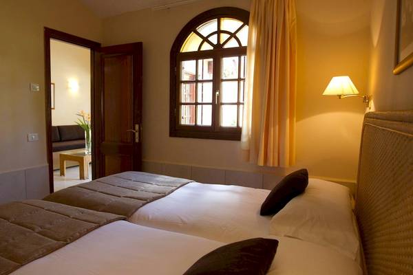 Schlafzimmer im Suites & Villas By Dunas mit zwei Betten, Fenster, Lampe und offenem Tür.