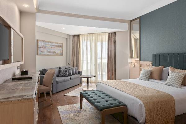 Luxuriöses Hotelzimmer im Xanadu Makadi Bay mit Doppelbett, Couch, Schreibtisch und Fernseher.