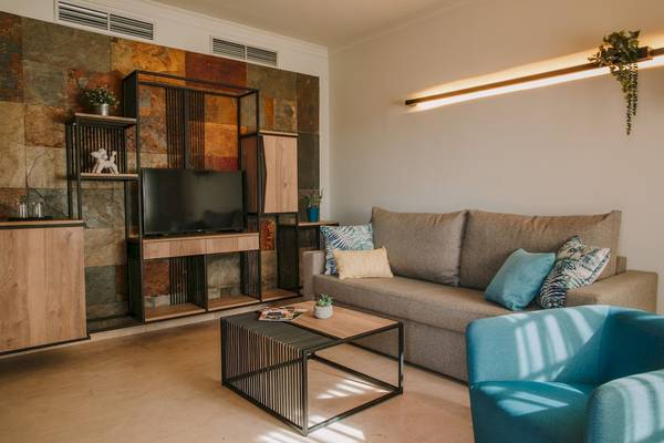Wohnzimmer im Suites & Villas By Dunas Hotel mit moderner Einrichtung und einem Fernseher an der Wand.