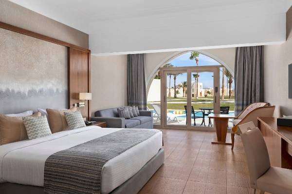 Hotelzimmer im Xanadu Makadi Bay mit Blick auf den Pool und Palmen.
