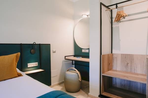 Schlafzimmer im Suites & Villas By Dunas Hotel mit Bett, Kissen, Nachttisch und Spiegel.