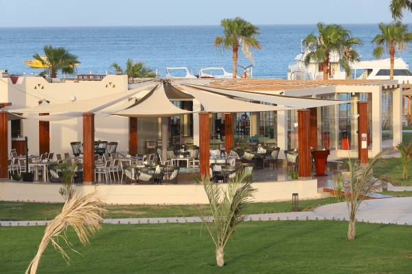 Außenbereich des Xanadu Makadi Bay Hotels mit Meeresblick und grüner Rasenfläche.