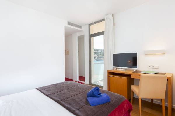 Hotelzimmer im Aimia Hotel mit Blick auf das Meer, mit Bett, Schreibtisch und Fernseher.