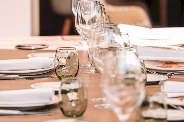 Gedeckter Tisch im Aimia Hotel mit Gläsern, Tellern und Servietten.