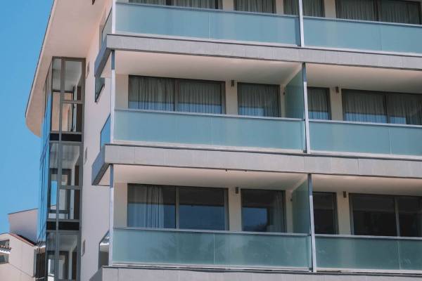 Außenansicht des Aimia Hotels mit mehreren Stockwerken und blauen Glasbalkonen.