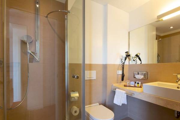 Badezimmer im Aimia Hotel mit Dusche, Toilette und Waschbecken.