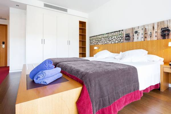 Schlafzimmer im Aimia Hotel mit zwei Betten, weißen Kissen und blauen Handtüchern.