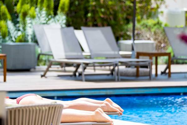 Personen liegen auf Liegestühlen am Pool des Aimia Hotels