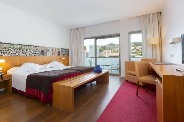Hotelzimmer im Aimia Hotel mit zwei Betten, Balkon und Schreibtisch.