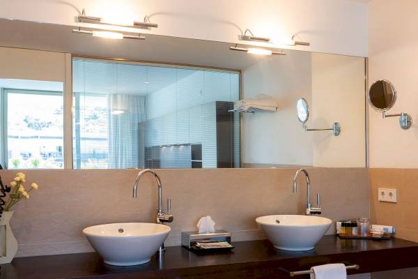 Badezimmer im Aimia Hotel mit zwei Waschbecken und Spiegeln.