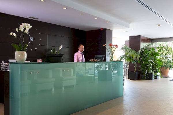 Empfangsbereich mit einem Mann in einem rosa Hemd im Aimia Hotel