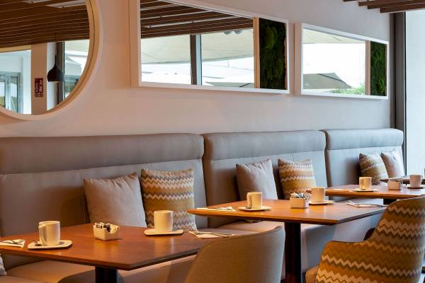Innenbereich des Aimia Hotels, Tisch und Stühle in einem Restaurant mit modernen Möbeln und Dekoration.