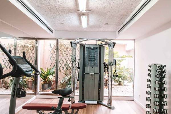 Fitnessbereich des Aimia Hotels mit Geräten und Blick auf Pflanzen.