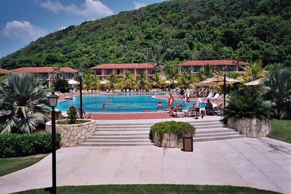 Außenbereich des Memories Jibacoa Resorts mit Swimmingpool und bergigem Hintergrund.