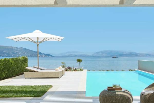 Außenpoolterrasse mit Sonnenliegen, Sonnenschirm und Blick auf das Meer im Hotel Ikos Dassia.