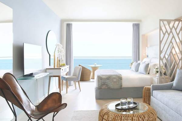 Zimmer im Ikos Dassia Hotel mit Meerblick, Bett, Schreibtisch, Fernseher und Möbeln.