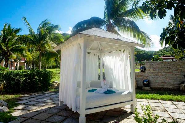 Weißer Liegestuhl im Freien im Memories Jibacoa Resort mit Vorhängen und Dekorententen.