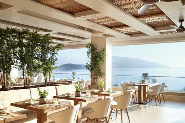 Innenbereich des Ikos Dassia Hotels, Restaurant mit Blick auf das Meer und Berge.