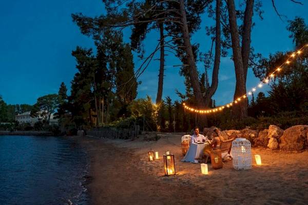 Romantisches Essen am Strand bei Abend mit Kerzen und Lichterketten.