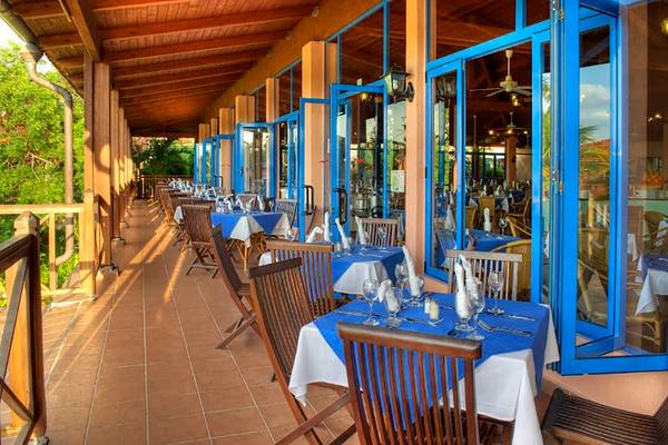 Terrasse des Memories Jibacoa Resorts mit blauen Türen und Tischen.