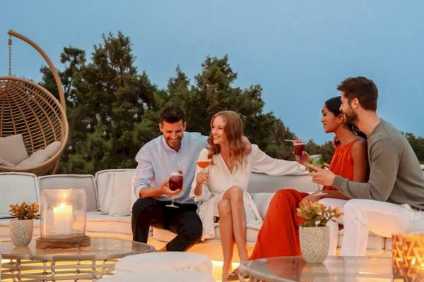 Zwei Paare sitzen auf einer Couch auf der Terrasse und trinken Cocktails.