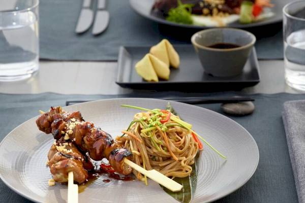 Ein Teller mit asiatischem Gericht im Hotel Ikos Odisia, bestehend aus gegrilltem Fleisch und Nudeln.