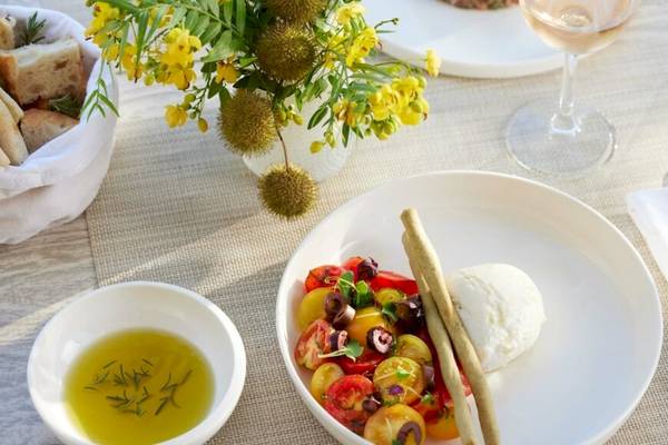 Ein Tisch im Hotel Ikos Odisia mit einer Schüssel frischem Gemüsesalat, einer Vinaigrette und Mozzarella.