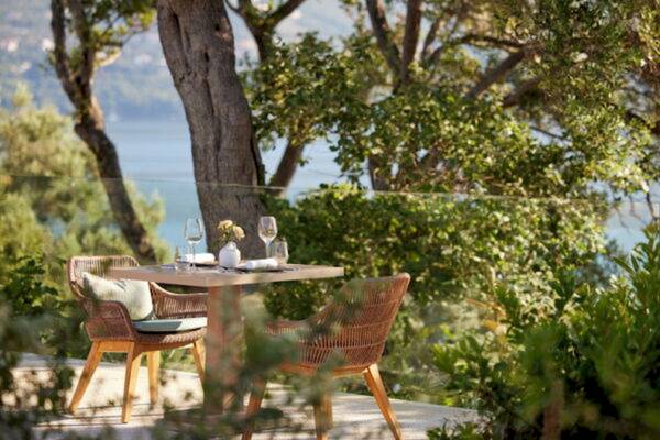 Gartentisch des Ikos Odisia Hotels mit Blick auf das Wasser und Bäumen