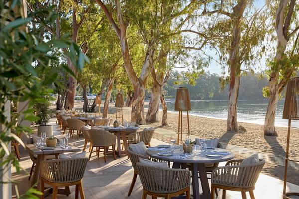 Strandrestaurant des Ikos Odisia Hotels mit Tischen und Stühlen unter Bäumen