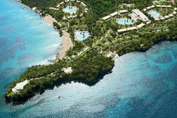 Luftaufnahme des Ikos Odisia Hotels an der Küste mit Pools und Gebäuden.