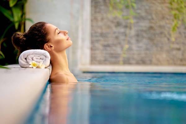 Eine Frau genießt entspannt im Pool mit einem Handtuch und Blumen