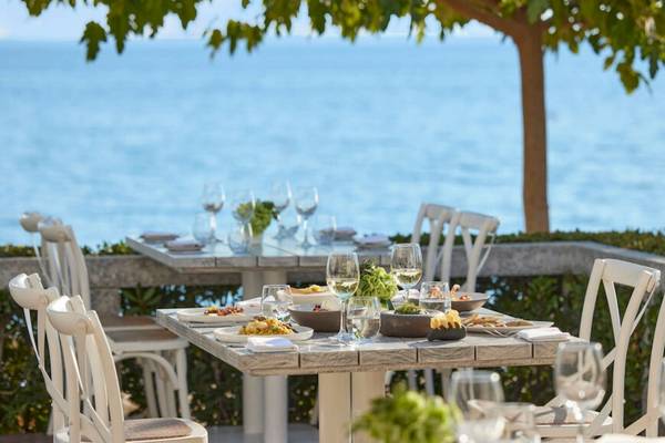 Ein Tisch auf der Terrasse des Ikos Olivia Hotels mit Blick auf das Meer und gedeckten Mahlzeiten.