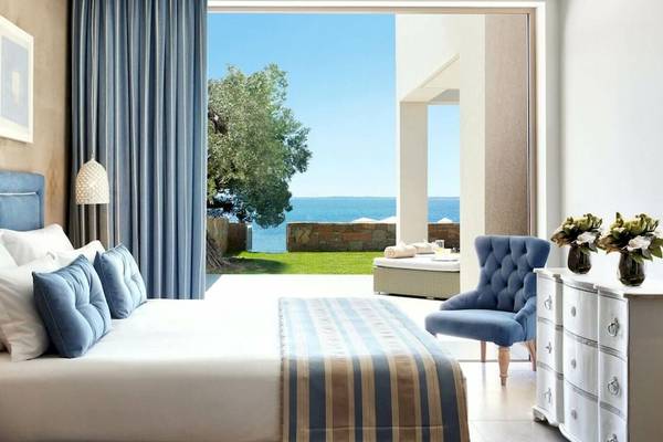 Schlafzimmer im Ikos Olivia Hotel mit Blick auf das Meer und eine Terrasse davor.