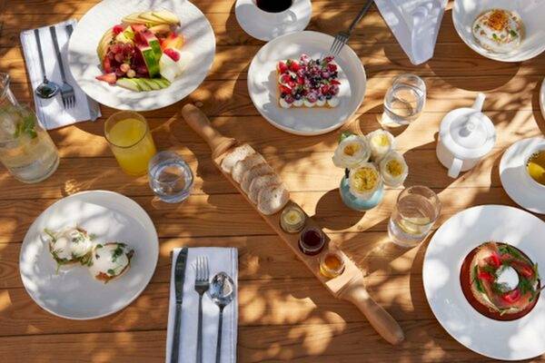 Frühstücksbuffet im Ikos Olivia Hotel mit verschiedenen Gerichten, Früchten und Getränken auf einem hölzernen Tisch.